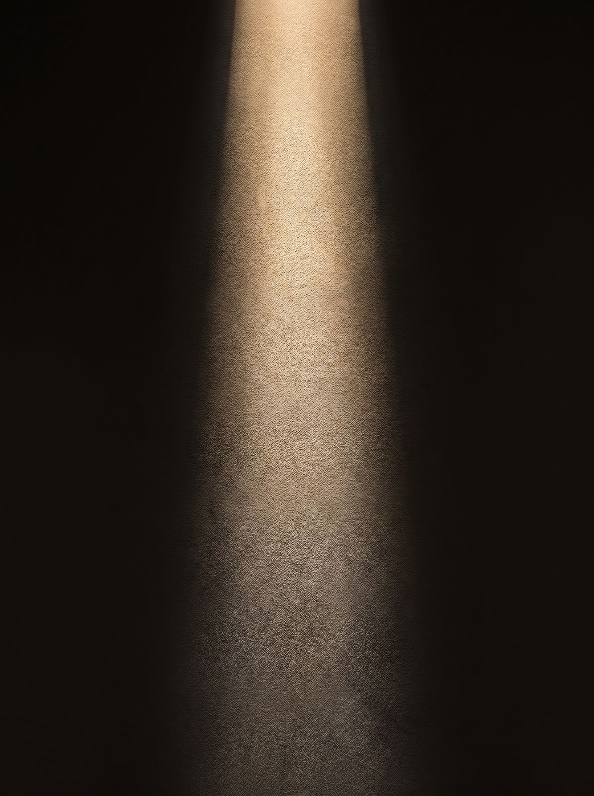 A column of warm gold light on a dark plaster wall